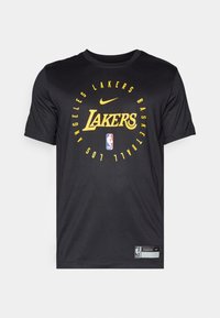 T-shirt noir à manches courtes avec le texte "Lakers" en jaune, le logo NBA et la marque Nike dans un design circulaire. Fabriqué en tissu léger.