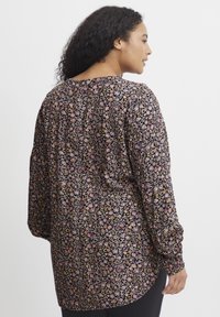 Garais piedurkņu blūze melnā audumā, ar ziedu rakstu rozā, purpura un dzeltenās krāsās. Brīvā piegriezuma, ar savilktām piedurknēm.