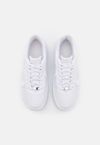 Baskets en cuir blanc avec une texture lisse, bout rond, détails perforés, lacets plats et un accent métallique sur la languette.