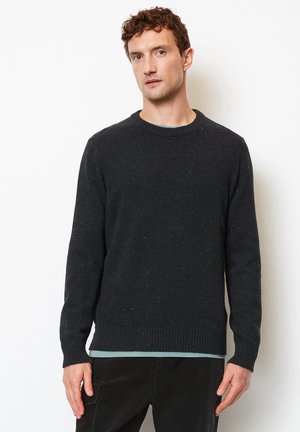 Dunkelgrauer Strickpullover mit Rundhalsausschnitt, gerippten Bündchen und Saum. Hat eine gesprenkelte Textur und eine lockere Passform, die über einer hellen Grundschicht getragen wird.