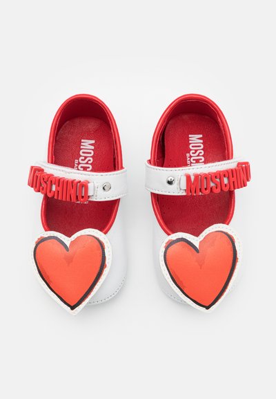 White leather shoes with red accents and a heart-shaped design on the front. Features a Velcro strap and textured inner lining.