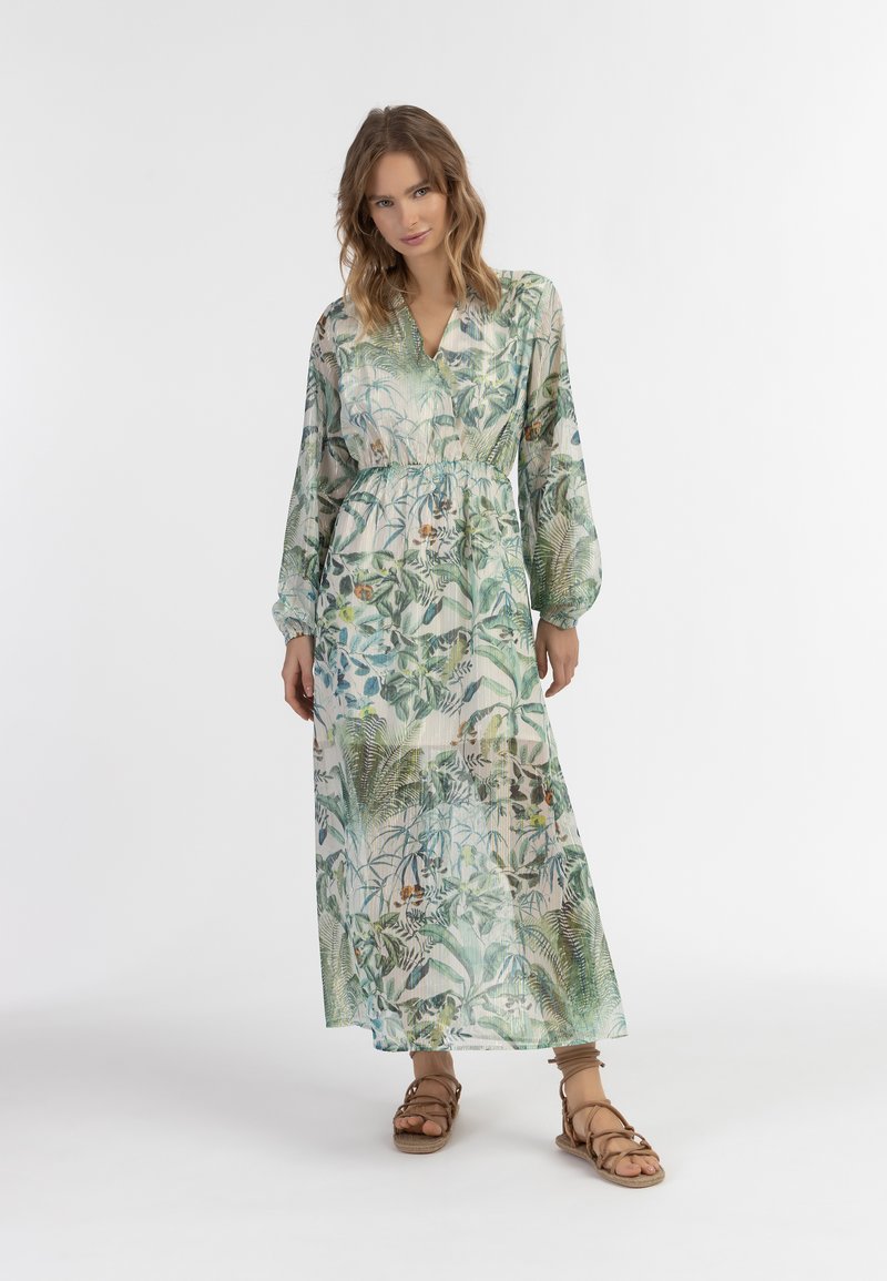 Rochie maxi florală dintr-un material ușor și transparent. Prezintă imprimeuri cu frunze verzi și albastre, cu mâneci lungi și o talie strânsă.