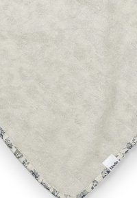 Pehmeä, kudottu pyyhe vaaleanharmaana, joka on teksturoitu pinnaltaan. Siinä on koristeellinen sininen kukkareunus ja pieni etiketti reunassa.