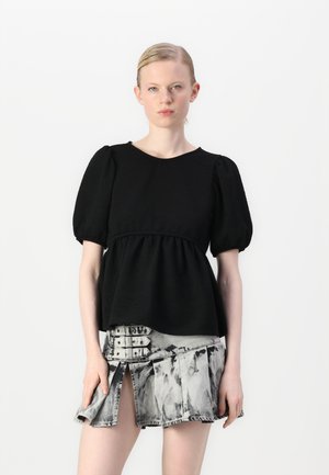 Black peplum top with short puff sleeves, textured fabric, paired with a gray denim skirt featuring a distressed pattern and side slit.