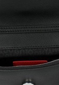 Borsa in pelle nera con apertura a zip. All'interno presenta un elegante portacarte rosso su una fodera in tessuto nero. Dettagli in hardware argentato visibili.