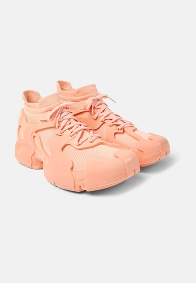 Sneakers featuring a soft peach mesh upper, ribbed ankle collar, and unique rubber overlay design with reinforced toe and heel accents.