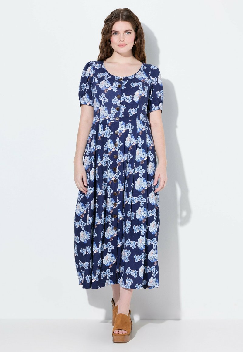 Květinové námořnické šaty s krátkými rukávy, kulatým výstřihem a knoflíkovým zapínáním vpředu. Mají rozšířený lem a květinový vzor v světle modré a růžové barvě.