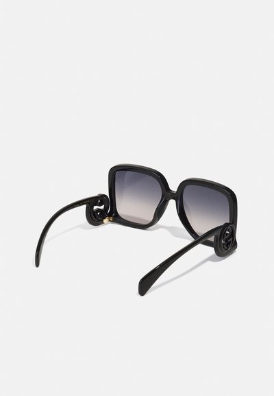 Gafas de sol negras cuadradas con lentes degradados. La montura gruesa presenta un diseño esculpido en las patillas. Acabado elegante y brillante en toda la pieza.