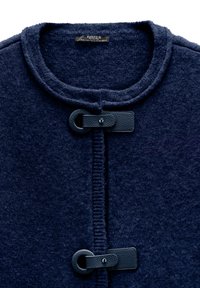 Granatowy sweter z dzianiny z okrągłym dekoltem, prążkowanymi wykończeniami oraz skórzanymi zapięciami na przodzie.