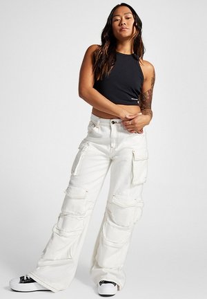 Pantalones cargo blancos con múltiples bolsillos, combinados con una blusa halter negra. Los pantalones tienen costuras visibles y un ajuste suelto y relajado.