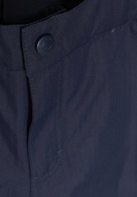 Mørkeblå bukser med herringbone-mønster, med en solid knaplukning og synlige søm langs sømmene.