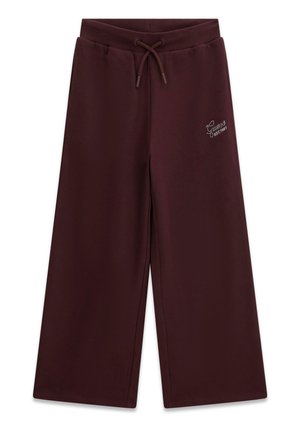Pantalon de survêtement marron foncé à jambes larges avec taille à cordon et petit logo blanc « Guess EST. 1981 » sur la partie supérieure de la cuisse gauche.