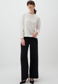 Lichtgewicht crème trui met een textuurpatroon van bloemen, gecombineerd met zwarte high-waisted broeken, met een recht model en stijlvolle hakschoenen.