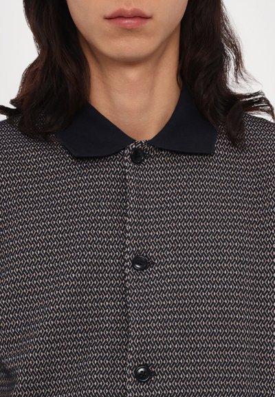 Πουκάμισο με κολάρο και γεωμετρικό σχέδιο σε ναυτικό και μπεζ χρώμα, με μαύρα κουμπιά και υφασμά�τινη υφή.