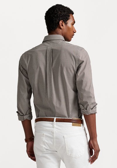 Brown and white checkered shirt with a standard collar, rolled sleeves, and a back yoke design, paired with white pants and a brown belt.