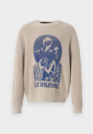 Maglione lavorato a maglia beige con grafica blu di una persona che tiene un fiore e testo "Les Benjamins" sul davanti.
