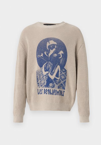 Beige kötött pulóver, elöl kék grafikával egy személyről, aki virágot tart, és a "Les Benjamins" felirattal.