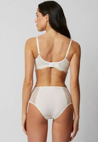 Set di reggiseno in pizzo bianco e slip a vita alta. Presenta accenti in pizzo floreale, tessuto morbido, spalline regolabili e chiusura posteriore a gancio e occhiello.