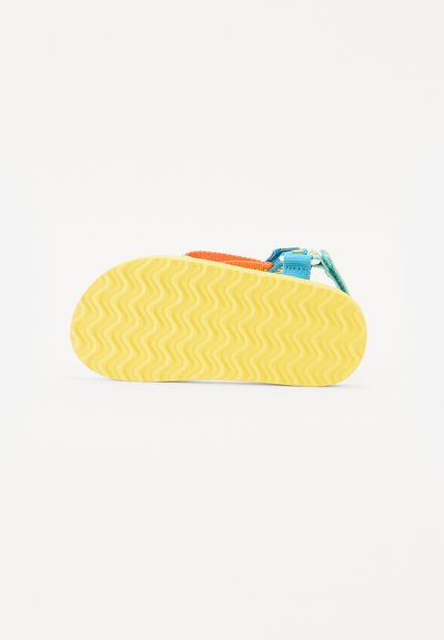 Gesloten teen sandaal met een gele rubberen zool met een golvend patroon, blauwe en oranje banden, plus een veilige klittenbandsluiting.