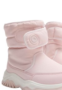 Roze laarzen met een zachte stoffen bovenkant, klittenbandsluiting en een witte rubberen zool met een golvend ontwerp, geschikt voor koud weer.