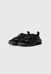 Schwarze Sneakers aus Leder und Wildleder mit runder Form, strukturierten Details, Schnürdesign und Gummisohlen.