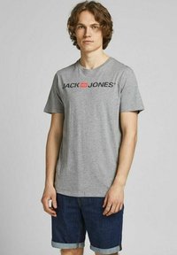 Graues Baumwoll-T-Shirt mit einem schwarzen, aufgedruckten Logo "JACK & JONES" auf der Vorderseite, kombiniert mit Jeansshorts mit umgeschlagenen Säumen.