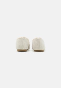 Pantoufles grises en feutre avec une douce bordure rose en peluche, un design à bout rond, une semelle plate beige et des coutures visibles à l'arrière.