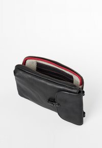 Portafoglio in pelle nera con chiusura a zip, interno rosso e a righe, multiple fessure per carte e dettaglio con bottone a pressione sul davanti.