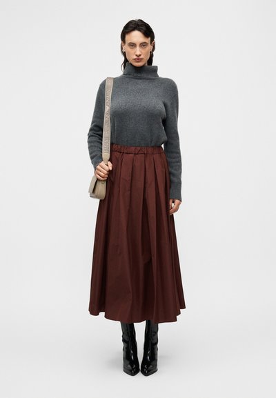 Γκρι πλεκτό πουλόβερ με ζιβάγκο, μπορντό πλισέ μέσης φούστα, μαύρες μπότες με τακούνι και μπεζ τσάντα ώμου με λουράκι με λογότυπο.