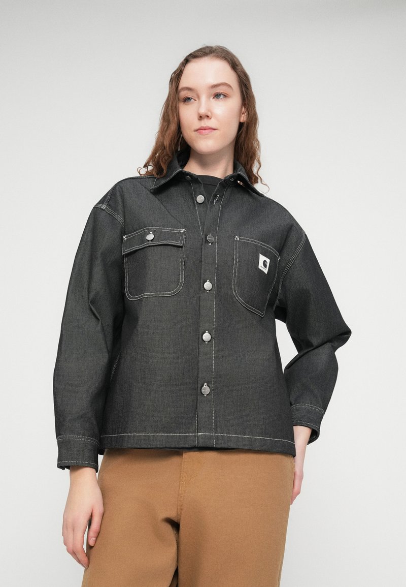 Mørk denimskjorte med struktureret design, der har sølvknapper, to brystlommer og kontrastsyning. Lange ærmer, krave.