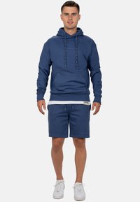 Marineblauwe hoodie met een voorzak en een trekkoord, gecombineerd met bijpassende marineblauwe shorts, met elastische tailleband en logo-detail.