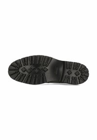 Suela de zapato de goma negra con surcos profundos, ranuras y patrones hexagonales. Textura suave con líneas horizontales cerca del talón.