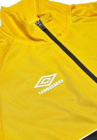 Giacca gialla in poliestere con colletto alto, zip frontale e dettagli neri. Presenta il logo bianco "Umbro" sul lato sinistro.