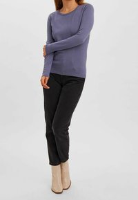 Pull léger violet clair à manches longues avec un motif texturé, col rond et poignets côtelés, associé à un jean noir et des bottines beige.