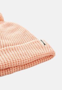 Dziana czapka w jasnoróżowym kolorze, z fakturowanym wzorem w wafle. Haftowana metka na mankiecie dodaje charakterystycznego, markowego akcentu.
