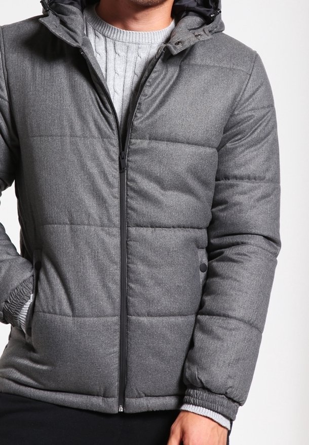 Grå dunjakke med lynlås foran, hyggelig hætte, ribstrikkede manchetter og synlige sømme, med en tekstureret stof og quiltet design.