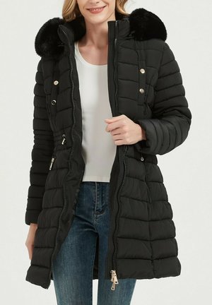 Manteau matelassé noir avec une fermeture éclair à l'avant, des boutons décoratifs et une capuche doublée de fausse fourrure. Il présente une coupe courte et des détails côtelés aux manches.