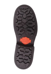 Suela de bota de goma negra con un patrón de textura y un logo incrustado de Harley-Davidson en rojo en el centro.