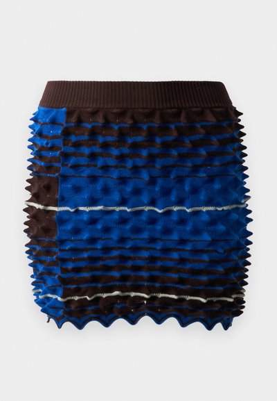 Kék és barna textúrájú sort, bordázott felsőrésszel, váltakozó csíkokban megemelt mintázattal és hullámos szegéllyel.