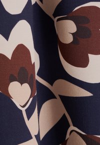 Tessuto stampato con grandi motivi floreali astratti nei colori bordeaux, crema e blu navy, caratterizzato da una superficie texturizzata e una caduta morbida.