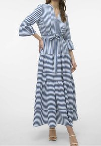 Vestido maxi a rayas en azul y blanco, con escote en v, cintura ceñida con cinturón, mangas tres cuartos y falda en capas. Textura de tela suave.