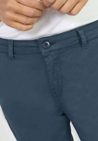 Chinos bleu foncé avec une texture lisse, dotés d'une fermeture à bouton, de passants de ceinture et de poches latérales, présentés au niveau de la taille.