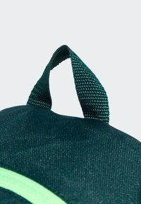 Zelena platnena torba okruglog oblika, s teksturiranim drškama i svijetlozelenom akcentnom prugom koja prolazi duž prednje strane.