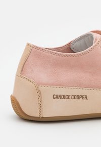 Pink suede and beige leather low-top sneaker features a textured upper, contrasting materials, and embossed branding on the side.