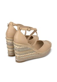 Sandali con zeppa in pelle beige, design a fascia incrociata, zeppa rivestita in juta e accenti metallici, punta arrotondata e chiusura con fibbia alla caviglia.
