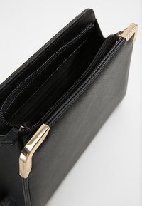 Borsa nera strutturata in tessuto con dettagli in oro; presenta scomparti con zip multipli per una migliore organizzazione.