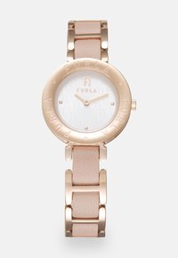 Furla laikrodis turi apvalų rožin�ės aukso nerūdijančio plieno korpusą, baltą ciferblatą, įspaudintą logotipą ir minkštos rožinės odos bei metalo dirželį.