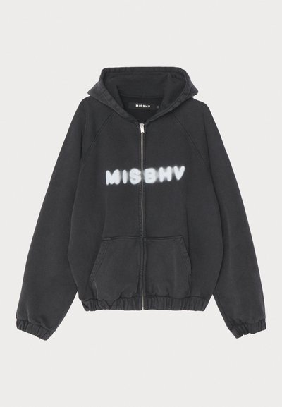 Schwarzer Hoodie mit Reißverschluss vorne, gerippten Bündchen und Saum. Mit „MISBHV“ in graffiti-artigem weißen Schriftzug auf der Brust.