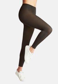Leggings neri con una finitura liscia e elasticizzata, caratterizzati da vita alta e vestibilità slim. Indossati con sneakers bianche.