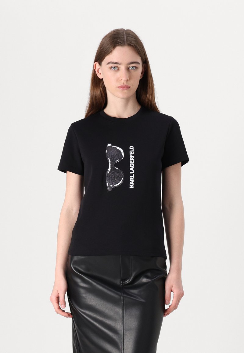 Juoda marškinėlių su grafiniu corseto dizainu ir baltu užrašu "KARL LAGERFELD". Trumpomis rankovėmis ir patogiu kirpimu.